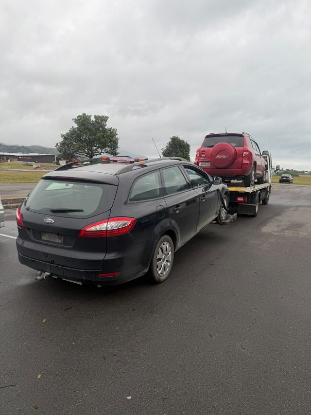 Dark station wagon ready for collection next to the tow truck