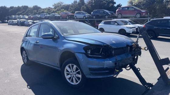 Damaged blue Volkswagen Golf loaded on a tow truck for recycling