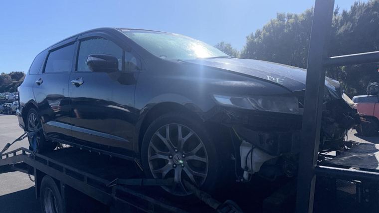 Dark people mover strapped onto a tow truck on its way to an Otago recycler